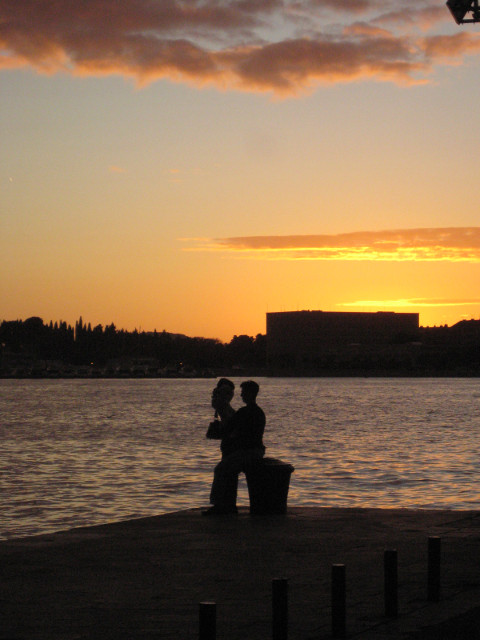 Sundown for two couple silhouetted against harbor sunset