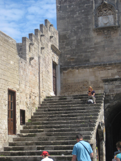 Above the crowd Young woman reading on the top stair at the town wall