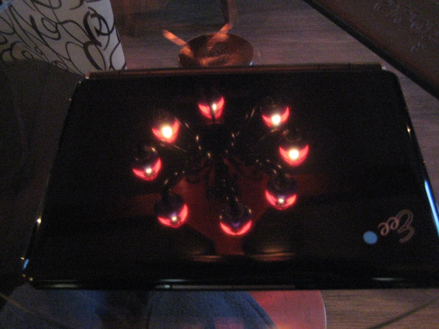 Laptop with Lights closed computer on table, lights reflected in top