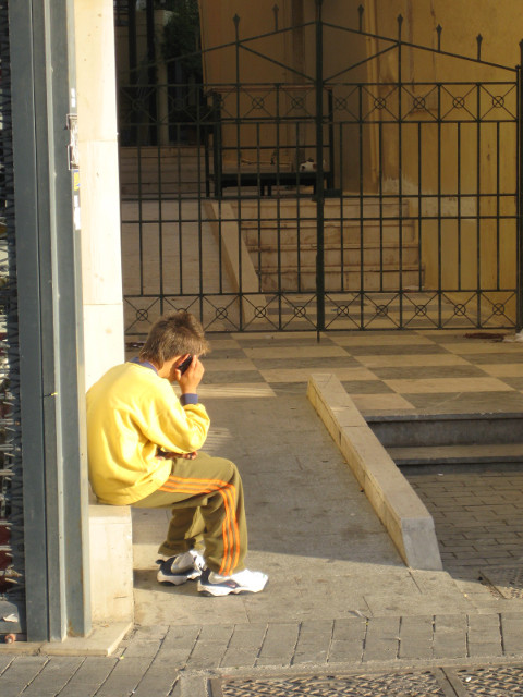 Not Weeping - Yakking sitting kid bent over mobile phone