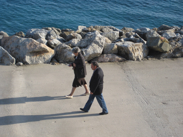 Strollers middle-aged couple walking on promenade by sea