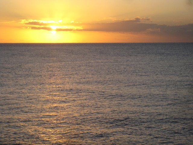 Toward the Rising Sun sun rising behind narrow cloud over ocean