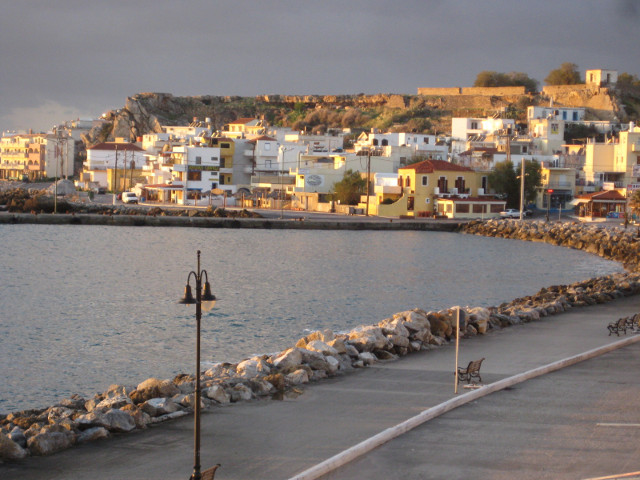 Curve of the Bay curving bay, sunlit houses, hilltop ruin, dark clouds