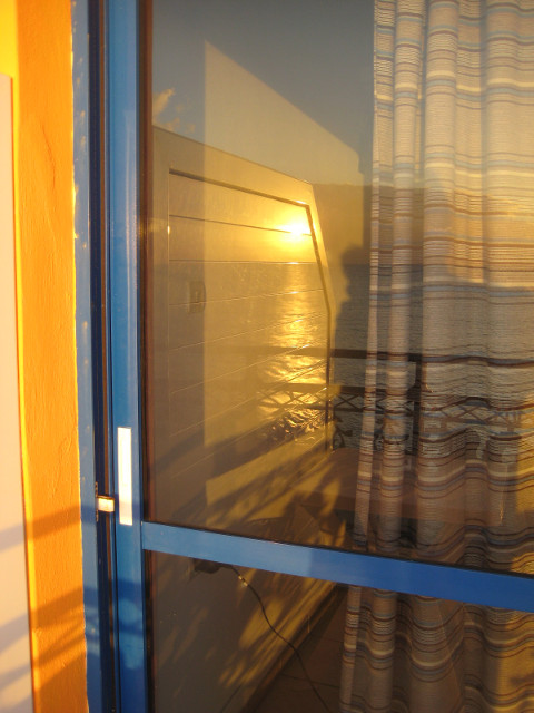 Balcony Reflections sunrise over sea, and balcony wall, reflected in sliding door