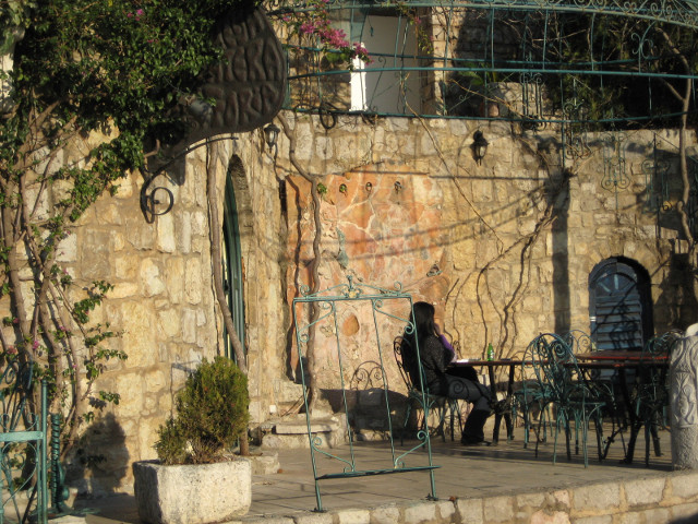 Cafe near Sveti Stefan woman at outdoor table in front of stone wall