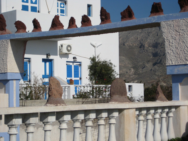 a home across the road white house, blue trim, dark pumice rock decor