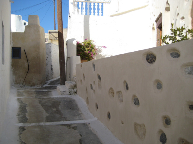 Old town street mabled-looking street, round-cornered bldgs, off-white wall with decorative stones