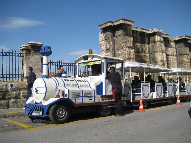 Same wall with choo-choo Tourist street train in front of ancient stone wall
