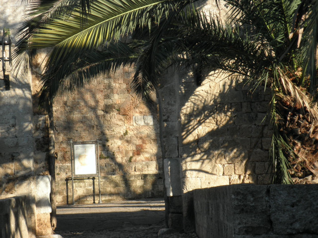 Entering Town palm tree by stone arch in stone wall revealing another stone wall with you-are-here