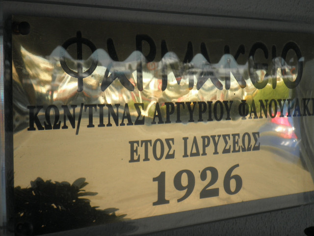 Farmakeio Sign polished sign, text obscured by reflections in top half