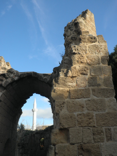 Old & New Time Religion white minaret framed in anciant stone archway