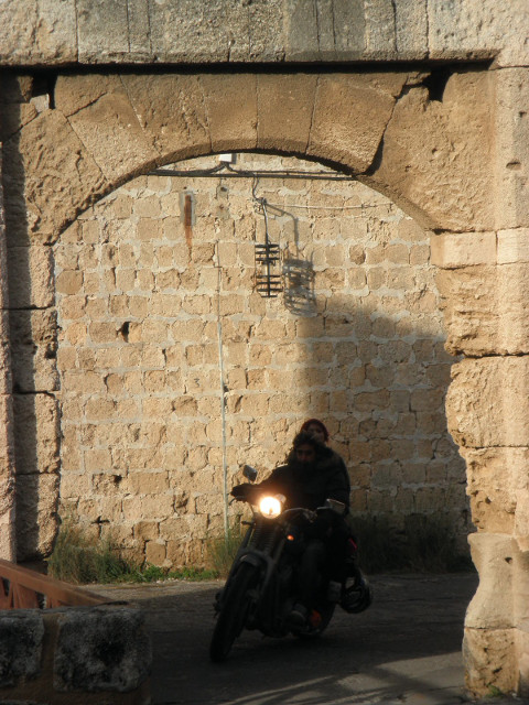 Looking in the Back Gate motorcycle rider emerging from stone arch