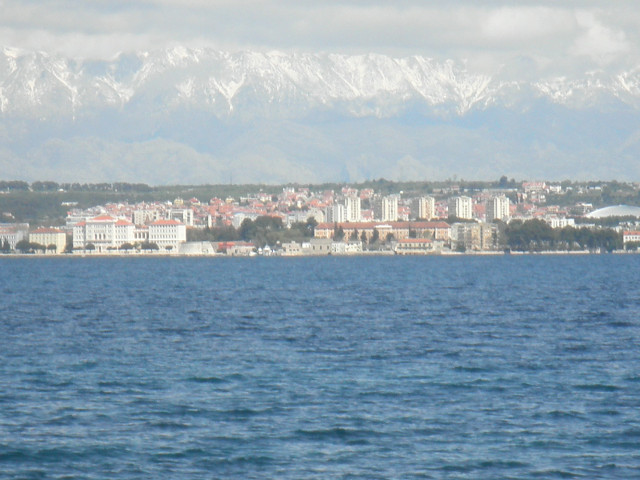 town from the ferry sea and distant town, backed by snow-covered mountains