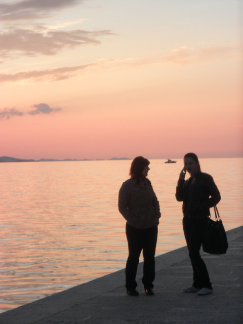 sunset couple standing in front of sea and sunset