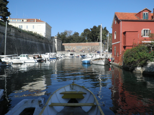 harbor inlet yachts parked between city wall and red barn-like restaurant