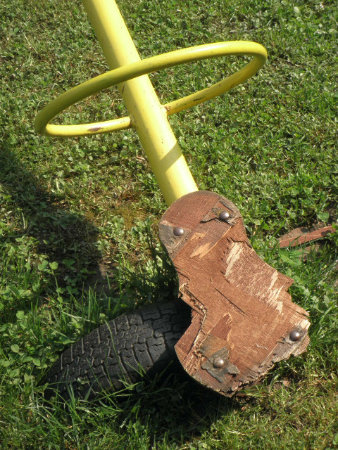 playground see-saw detail bright yelloe see-saw seat resting on a tire embedded in the ground