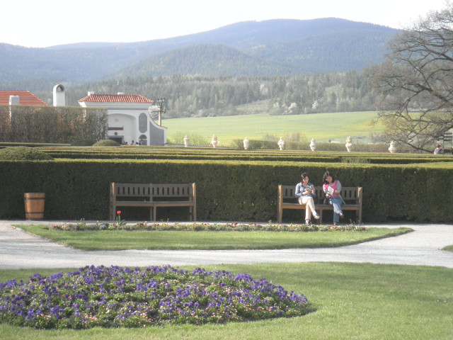 Bench Sitters Two tourists on a bench in front of a hedge maze