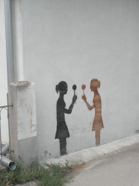 silhouettes two girls with lollipops, painted in silhouette on a white house wall